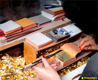Interleaving the gold leaves with tissue paper in books for sale   -   Click to view a larger resolution image